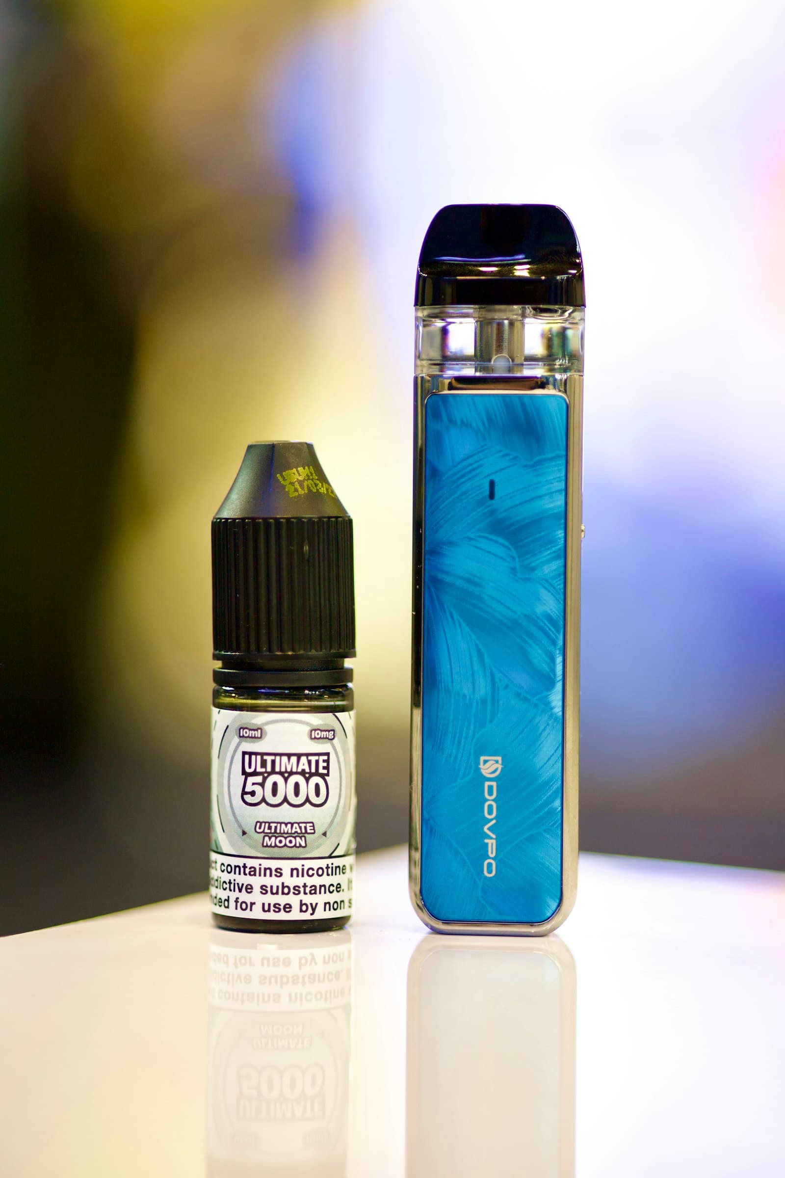 A small 10ml nicotine salt e-liquid bottle standing next to a pod vape kit